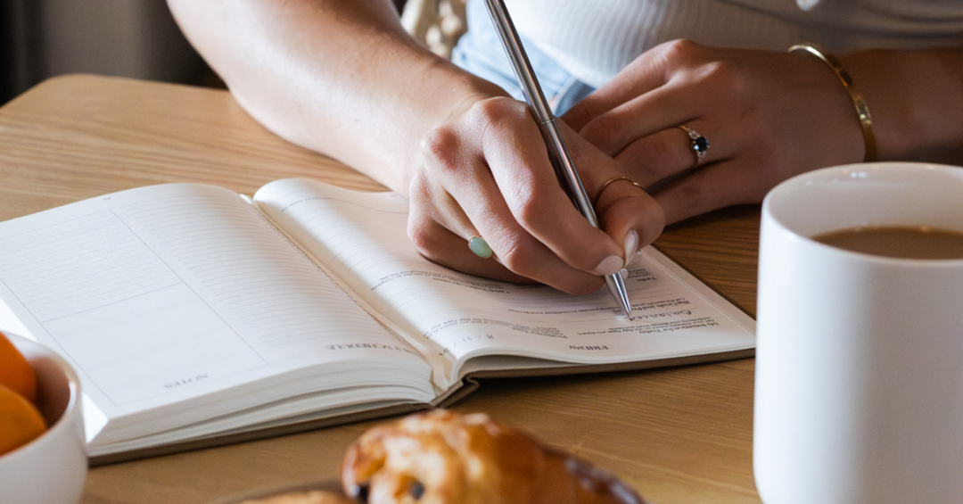 writing in a daily productivity planner